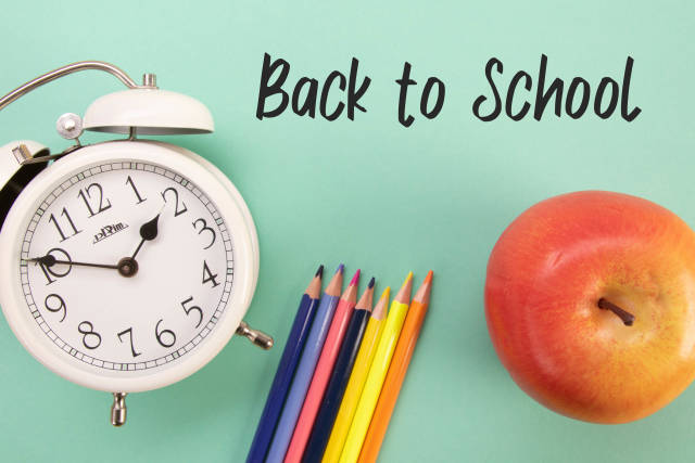 Alarm clock, colored pencils and apple with Back to School text
