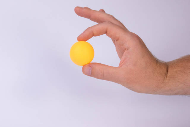 Hand holding table tennis ball on white background