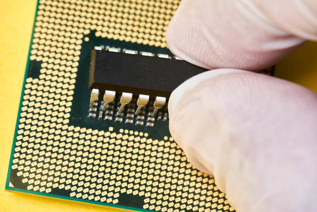 Electronic technician holding tweezers and assemblin a circuit board.