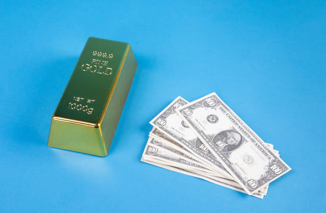 Gold brick with dollar banknotes on blue background