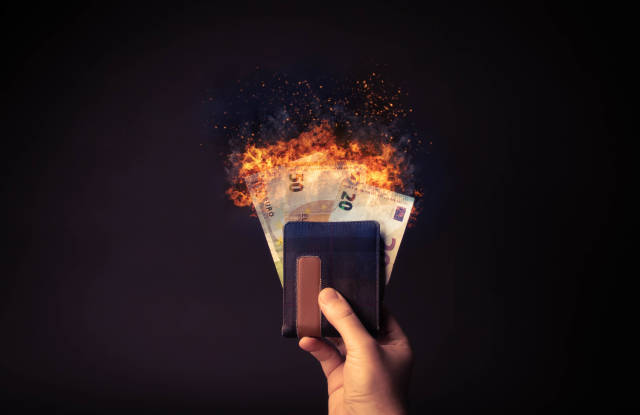 Hand holding wallet with euro money on fire