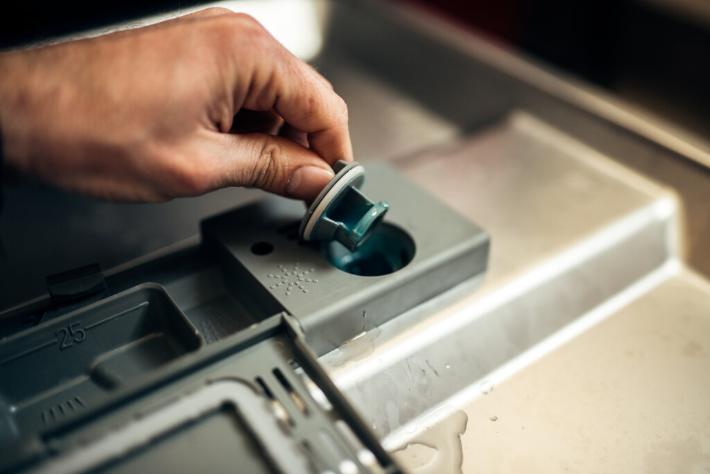 Man putting gel in dishwasher detergent box.