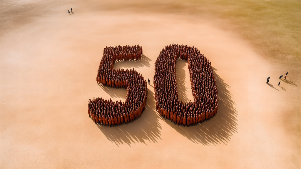Menschen formen die Zahl 50 auf einer weiten Sandfläche