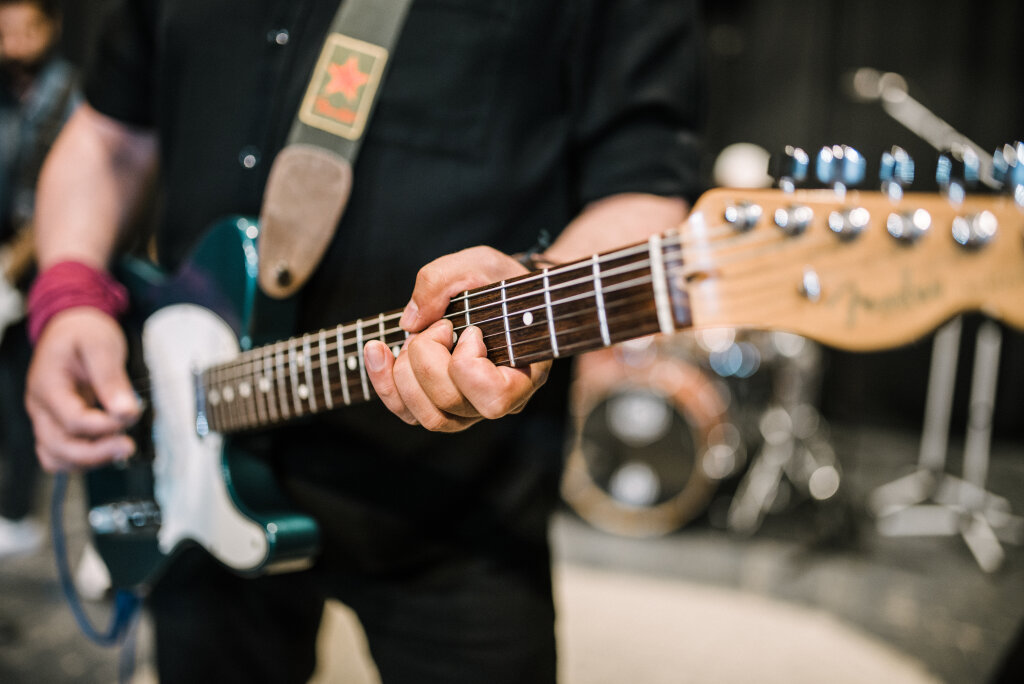 Guitarist performing live. Closeup of fingers on electric guitar neck.