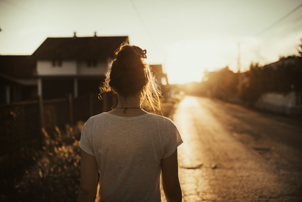 Woman walking down the street in the sunset.