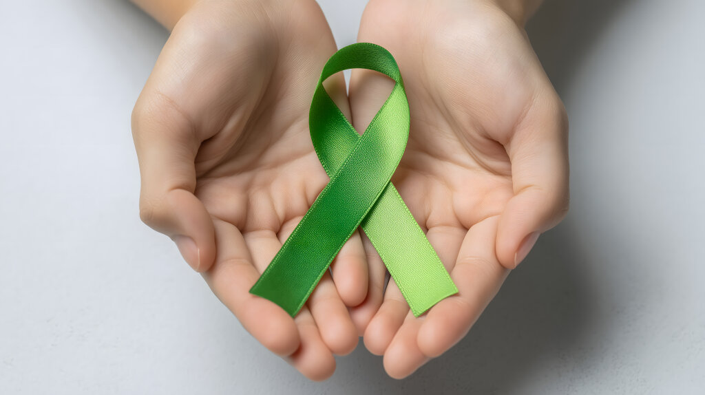 Grüne Schleife in Händen für mentale Gesundheit