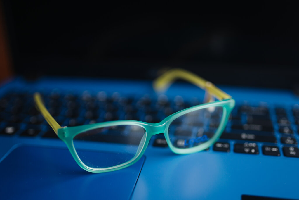 Close up of the glasses with light blue frame on a blue laptop.