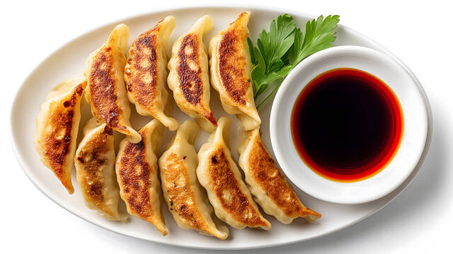 Gebratene Gyoza auf weißem Teller mit Sojasauce und Petersilie