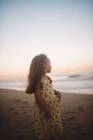 little girl on the beach looking at the sea.
