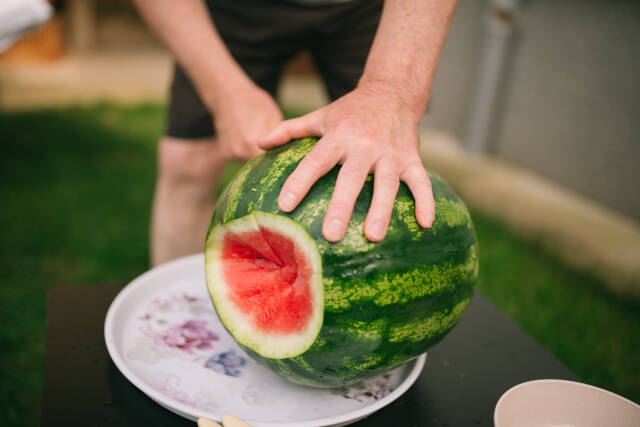 Man cuting watermelon in the yard.