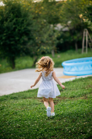 Girl in white dress running in the backyard.