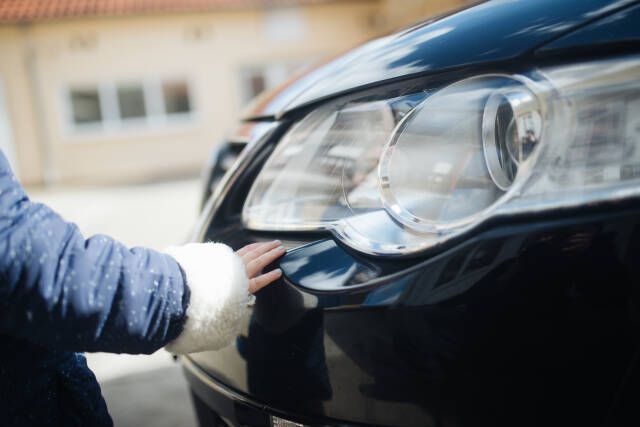 Young girls hand on a car headlight.