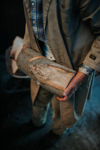 Old man carrying cut firewood with bare hands.