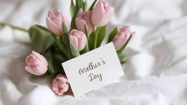 Tulpenstrauß mit Mother’s Day Karte auf Bettdecke