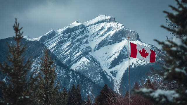 Kanadische Flagge vor verschneitem Berggipfel