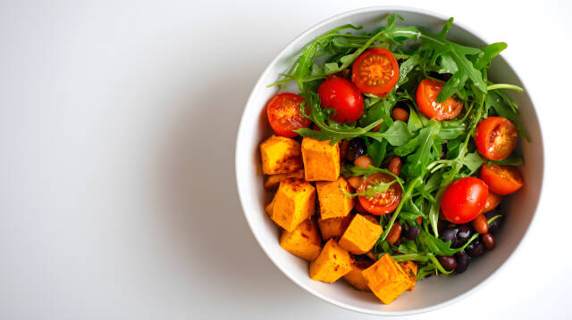 Vegane Bowl mit Süßkartoffeln Rucola und Tomaten