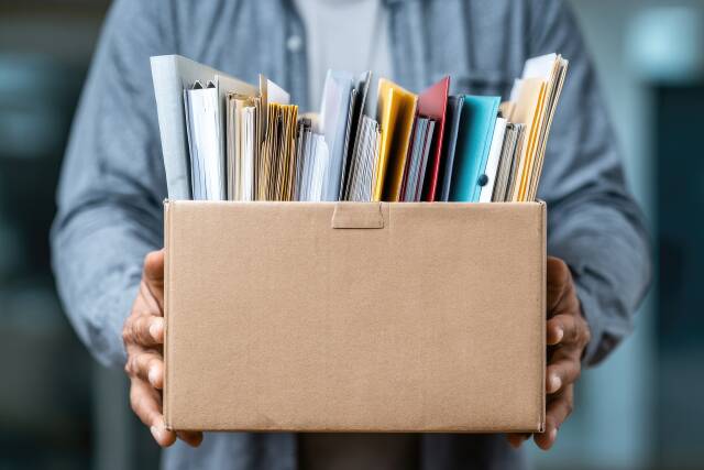 Mensch hält Umzugskarton mit Dokumenten und Akten