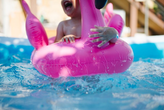 A cheerful child is splashing in a pool while