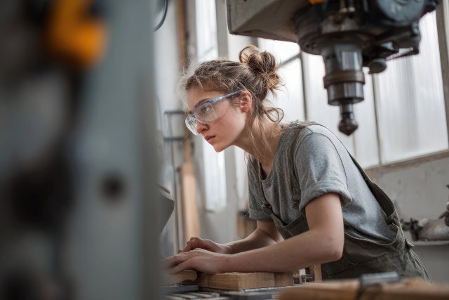 Junge Handwerkerin mit Schutzbrille bei der Arbeit