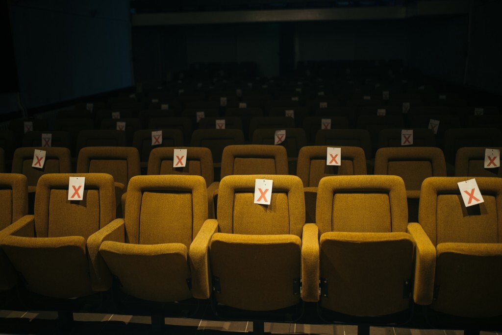 Rows of unoccupied theater seats display tags indicating unavailable spots for social distancing