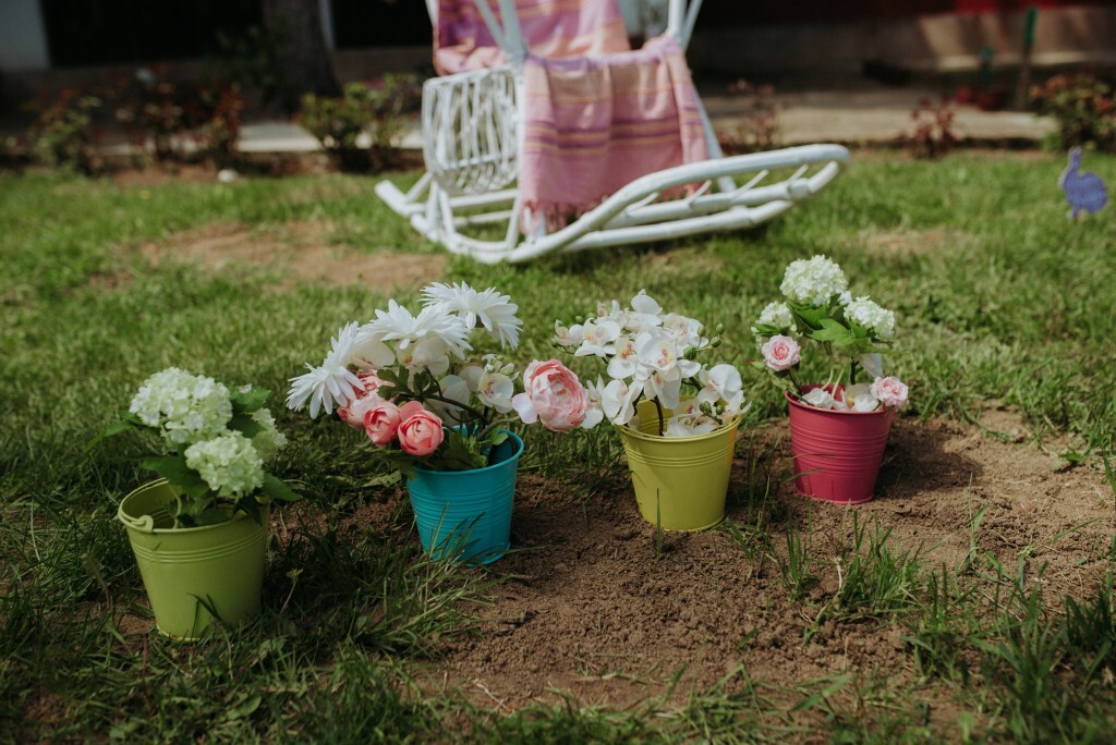 Colorful flower pots arranged on green grass with a rocking chair