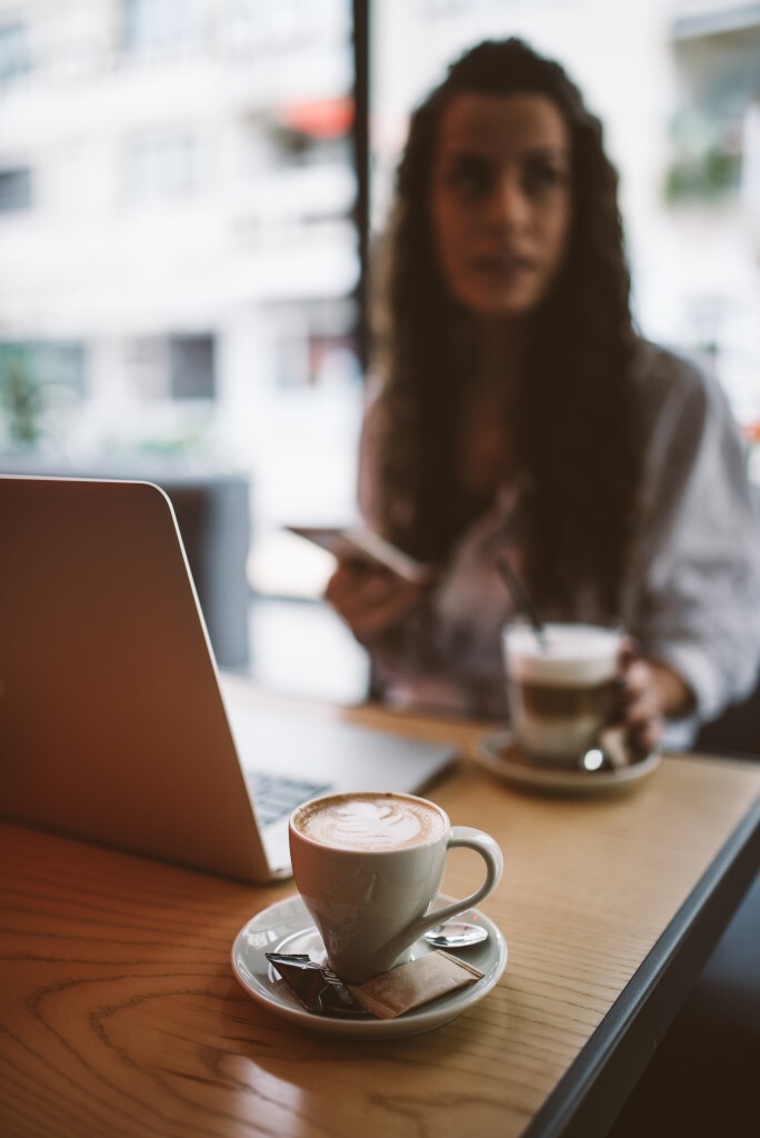 A woman with curly hair sits at a wooden table