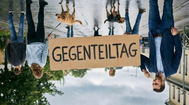 Gegenteiltag am 25.01.: Umgedrehte Szene mit Mann und Schild im Regen auf Straße