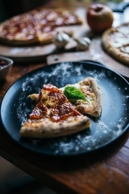 Two slices of pizza sit on a black plate