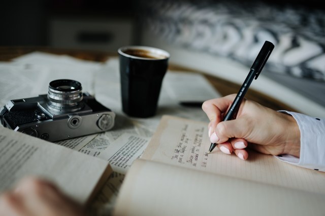 A person enjoys coffee while taking notes