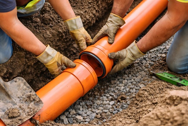 Arbeiter verlegen Kanalrohre im Boden