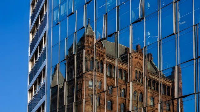 Glasfassade reflektiert historisches Gebäude